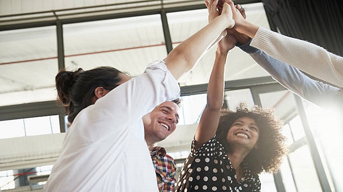 Photo d'un groupe de jeunes collègues de travail se congratulant au bureau - Activ Solutions