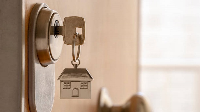 Gros plan sur une clé et un porte-clés « maison » dans la serrure d'une porte de haute sécurité - domicilier votre entreprise - Activ Solutions