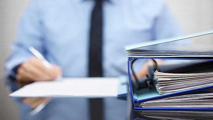 des classeurs contenant des documents sur le bureau d'un homme - constituer une société à Madagascar - Activ Solutions