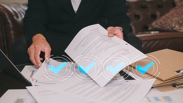 Un homme assis dans un bureau ou un canapé dans un salon analyse les données du rapport papier - domiciliation de société à Madagascar - Activ Solutions