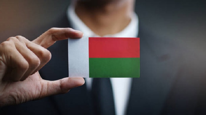 Homme d'affaires tenant une carte du drapeau de Madagascar - louer un espace de travail partagé - Activ Solutions